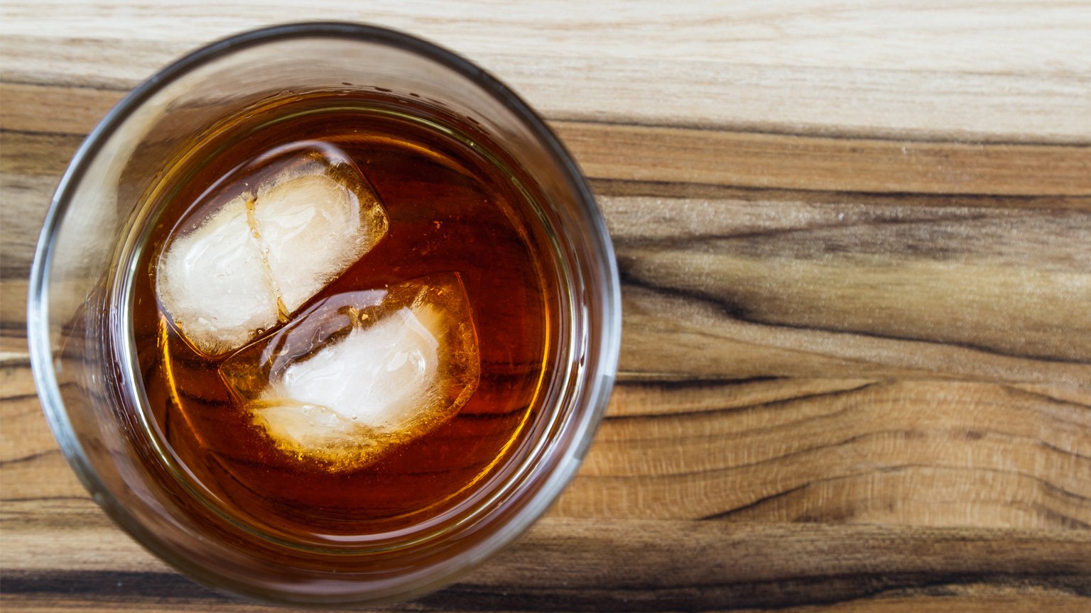 A glass of bourbon with two ice cubes.