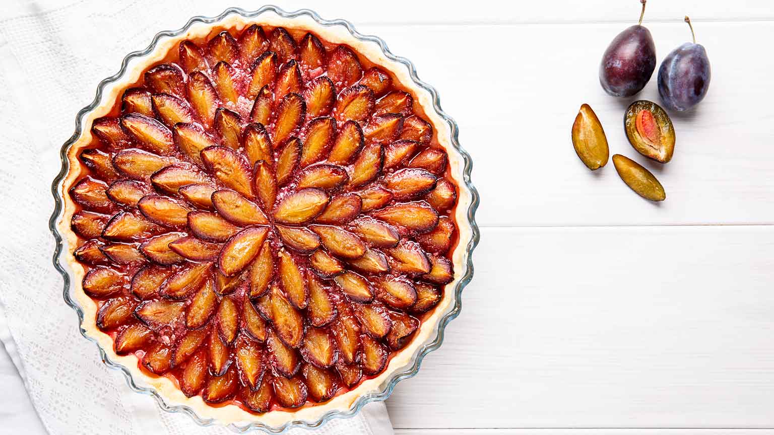 A damson tart with plums beside it