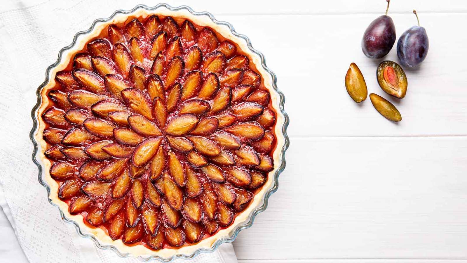 A damson tart with plums beside it